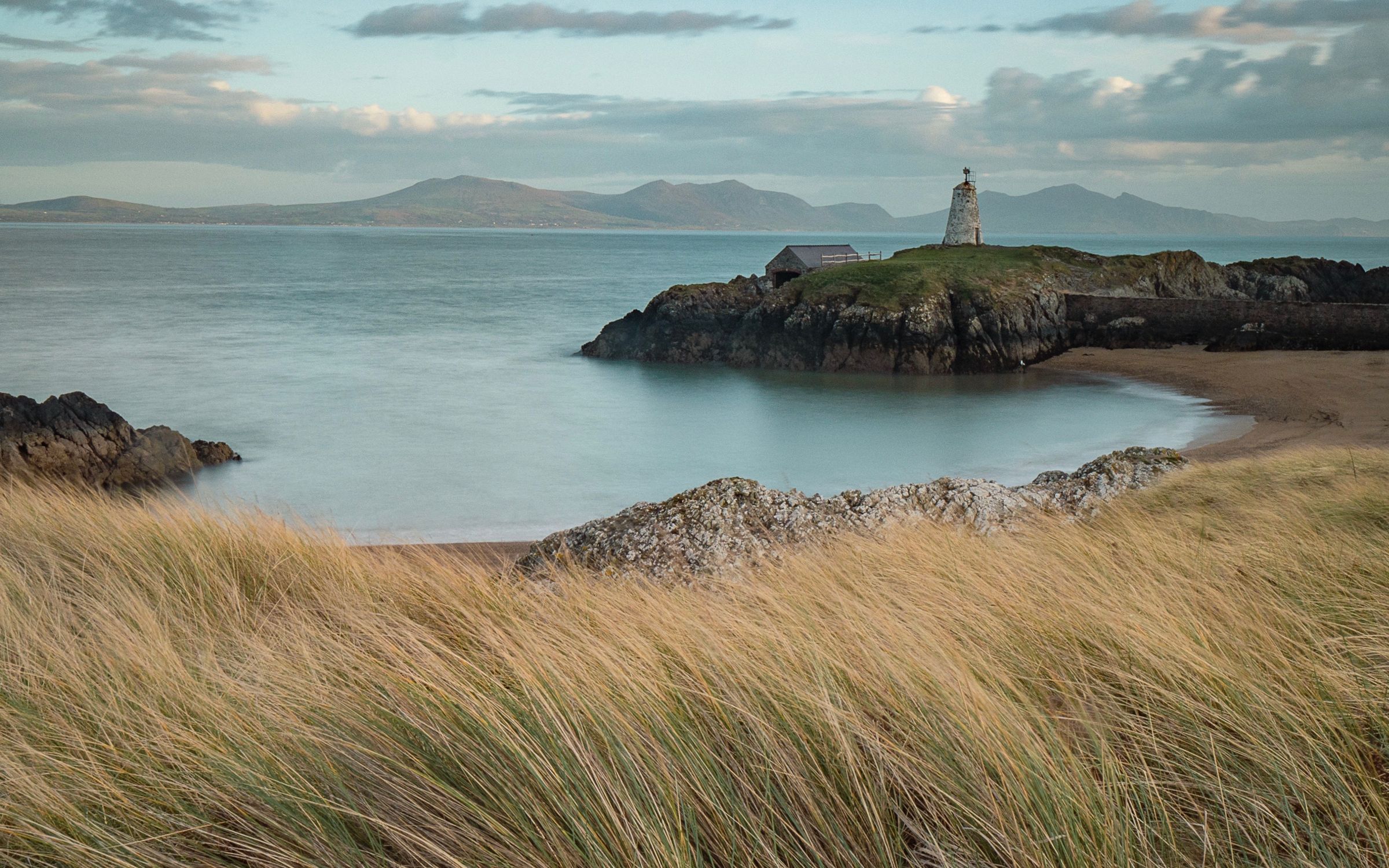 Tŵr Mawr lighthouse on Ynys Llanddwyn, Anglesey, with the mountains of Eryri across the strait at dusk